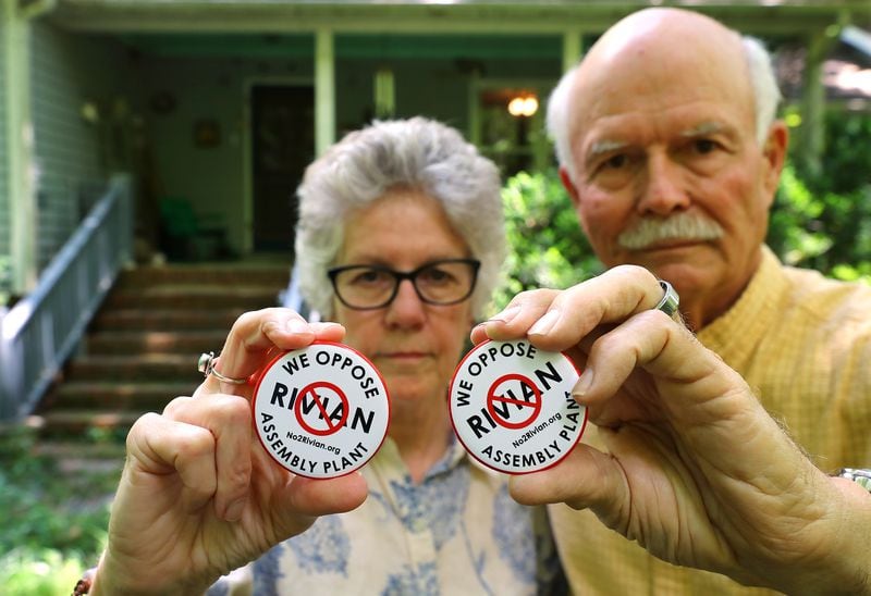 Penny and George West show off their anti-Rivian buttons outside their home near Madison. The couple says the future plant is the main issue they care about in the upcoming primary elections. 