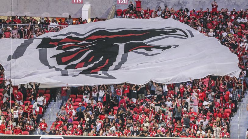 Falcons fans pass a giant flag in the stands during Saturday’s opening game at Mercedes-Benz Stadium.