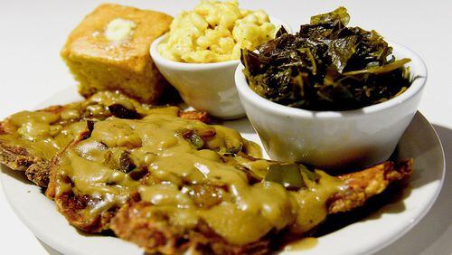 Smothered pork chops with sides of cornbread, macaroni and cheese and greens at Carmi Soul Food in Pittsburgh. (Pam Panchak/Pittsburgh Post-Gazette/TNS)