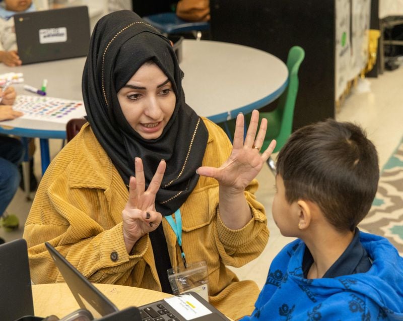Shakila Aimaq (left), a recent Afghan refugee who is studying to become a teacher, helps Sesal Gurung in Taylor Thomas' kindergarten class at the International Community School in Decatur. PHIL SKINNER FOR THE ATLANTA JOURNAL-CONSTITUTION