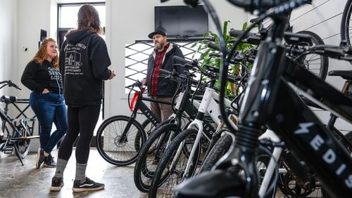 FILE: Emily Beach (left) and her husband Jeff (right) chat with  Edison Electric Bicycle shop manager Tyler Riberdy (center) on Thursday, Dec. 22, 2022. (Natrice Miller/natrice.miller@ajc.com)