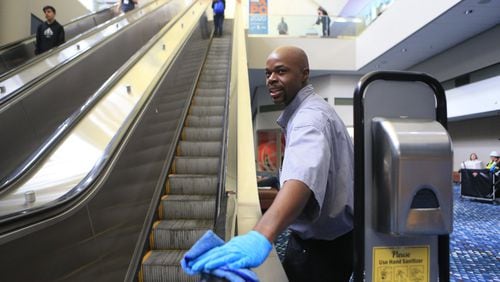 Dion Smith wipes down the escalator during the Construction Education Foundation of Georgia (CEFGA) career expo on Thursday, March 12, 2020, at the World Congress Center in Atlanta. This year, additional safety measures were implemented, including mandatory hard hats and wipe downs of surfaces people touch. CHRISTINA MATACOTTA, FOR THE ATLANTA JOURNAL-CONSTITUTION