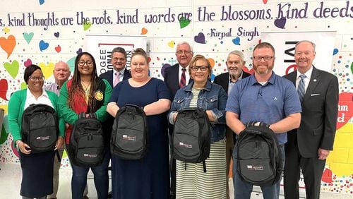 The 2024 Buntin Scholars show the backpacks they were given at the March 26 announcement in Dimon Magnet Academy. Posing with them are Muscogee County School District superintendent David Lewis (back row, far right) and retired MCSD superintendent Jim Buntin (back right, second from right), along with some members of the lunch group that donated $56,000 to establish the program in Buntin’s honor, paying for MCSD teachers from schools serving impoverished students to attend a national conference for professional development. (Photo Courtesy of Mark Rice)