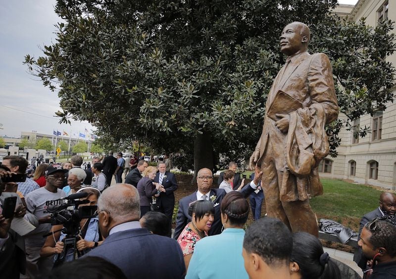 GEORGIA CAPITOL: Three years after the project was announced, this statue of MLK was unveiled on the Georgia Capitol grounds on Aug. 28, 2017âthe anniversary of the "I Have a Dream" speech. The 8-foot statue, one mile from King's birthplace, overlooks Liberty Plaza and stands uneasily beside a number of segregationists also venerated on the Capitol grounds. The project was championed by Gov. Nathan Deal and Rep. Calvin Smyre (D-Columbus), who stands center in this photo, with his hand on the statue. The Legislature approved the tribute as long as no taxpayer funds were used. The original sculptor, Andy Davis, died before the project could be completed. He was replaced by Martin Dawe, who based the pose and likeness on a famous photo of King walking with Bayard Rustin in Montgomery, Ala. (Bob Andres / bandres@ajc.com)