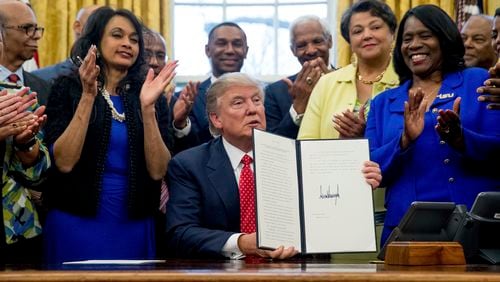 President Donald Trump holds up the Historically Black Colleges and Universities HBCU Executive Order after signing it, Tuesday, Feb. 28, 2017, in the Oval Office in the White House in Washington. (AP Photo/Andrew Harnik)