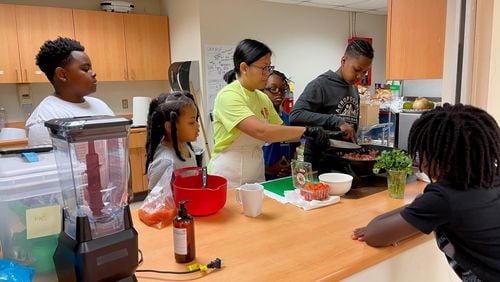 Cecilia Tran (center, in green), with the UGA Extension service, teaches campers how to make tacos at a 2023 summer camp. This year Tran, a registered dietitian, is running Let Them Cook, a new summer camp on teaching cooking skills.