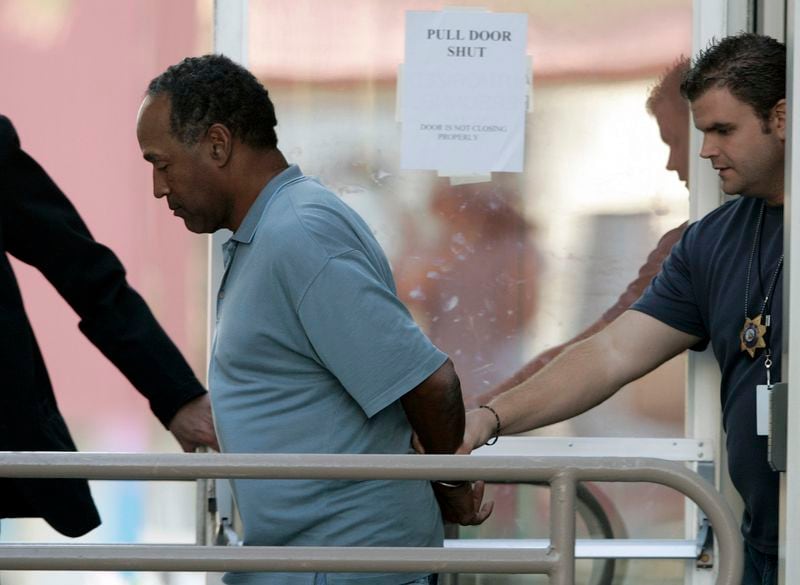 FILE - In this Sept. 16, 2007 file photo, O.J. Simpson is taken from the Las Vegas Police Investigative Services Division in Las Vegas. O.J. Simpson's attorney Malcolm LaVergne is now handling the deceased former football star, actor and famous murder defendant's financial estate. (AP Photo/John Locher, File)