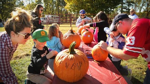 Kids and parents decorate pumpkins at the Fall Farm Fest at Lost Creek Reserve Saturday. The Miami County Park District hosts their biggest event of the year at the historic Knoop Homestead for thousands of people who attend the two day festival celebrating the agricultural heritage of Miami County. JIM WITMER/STAFF