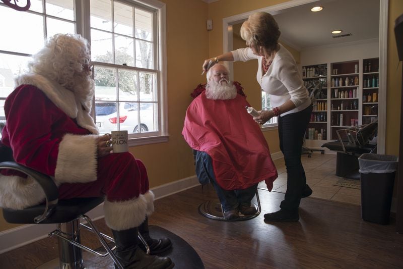 Hairstylist Sharon Franklin styles “Santa” Damon Duncan’s hair as “Santa” George Price watches during their touch-up visit at Mela Michael’s Salon in Roswell on Dec. 12, 2017. In addition to styling Santa Clauses’ hair, Sharon gives her clients tips on maintaining their look in between visits. ALYSSA POINTER / ALYSSA.POINTER@AJC.COM