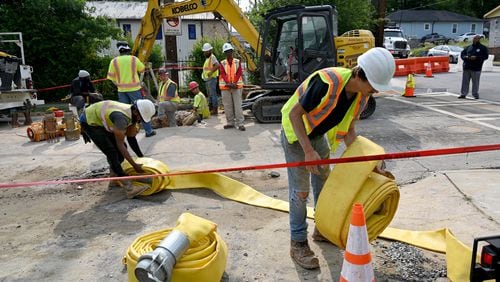 Workers move equipments in place as they work on to fix water main break at Joseph E. Boone Boulevard and James P. Brawley Drive, Saturday, June 1, 2024, in Atlanta. A water main that ruptured, causing thousands to lose access to water around Atlanta, was repaired Saturday morning but water may take several hours to be restored.(Hyosub Shin / AJC)