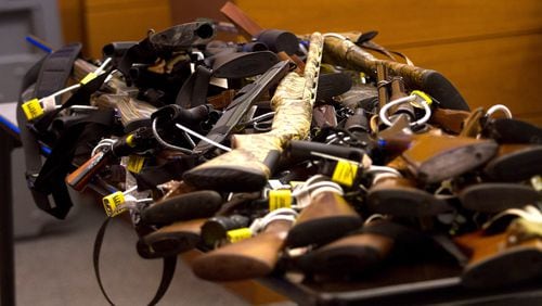 Tex McIver’s dozens of guns are piled onto table in court on Day 12 of McIver’s murder trial. Steve Schaefer / For the AJC