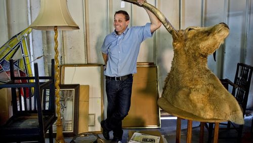 Brian Witherell rests on the horn of an ox while chatting about different California antiques in his warehouse in Sacramento. (Renee C. Byer/Sacramento Bee/TNS)