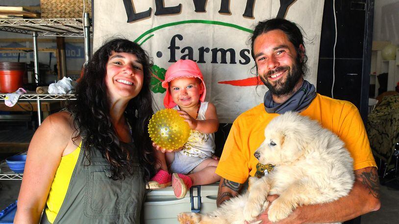 Ilana and Zach Richards, with their daughter Harlyn and new pup (a then-9-week-old Great Pyrenees named Mulch), pose in the barn before a tour of Levity Farms in Madison. Chris Hunt for The AJC