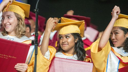 Marisela Lozada (center) and her classmates turn their tassels on their graduation cap during the commencement ceremony for Maynard Jackson High School at the Georgia World Congress Center in Atlanta on May 22, 2018.  ALYSSA POINTER/ATLANTA JOURNAL-CONSTITUTION