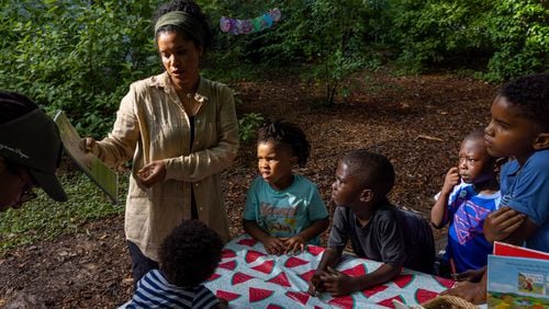 Shelby Stone-Steel, co-founder of Gather Forest School, shows students their yearbook at a park in Atlanta on Thursday, June 30, 2022. (Arvin Temkar / arvin.temkar@ajc.com)