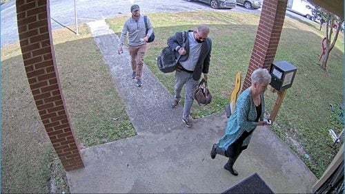 Scott Hall, a bail bondsman who flew from Atlanta to Coffee County and helped coordinate copying of election data, carries bags into the Coffee County elections office on Jan. 7, 2021. He's escorted by Cathy Latham, a fake elector for Donald Trump, and an unidentified man in a security camera video.