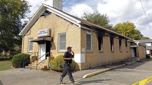A state fire marshal investigates the fire damaged Hopewell M.B. Baptist Church in Greenville, Miss., Wednesday, Nov. 2, 2016. “Vote Trump” was spray-painted on an outside wall of the black member church. Fire Chief Ruben Brown tells The Associated Press that firefighters found flames and smoke pouring from the sanctuary of the church just after 9 p.m. Tuesday. (AP Photo/Rogelio V. Solis)