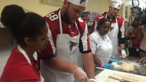Atlanta Falcons players Mike Peterson (center) and Ryan Schraeder work with Westside Works culinary students to prepare challah bread.