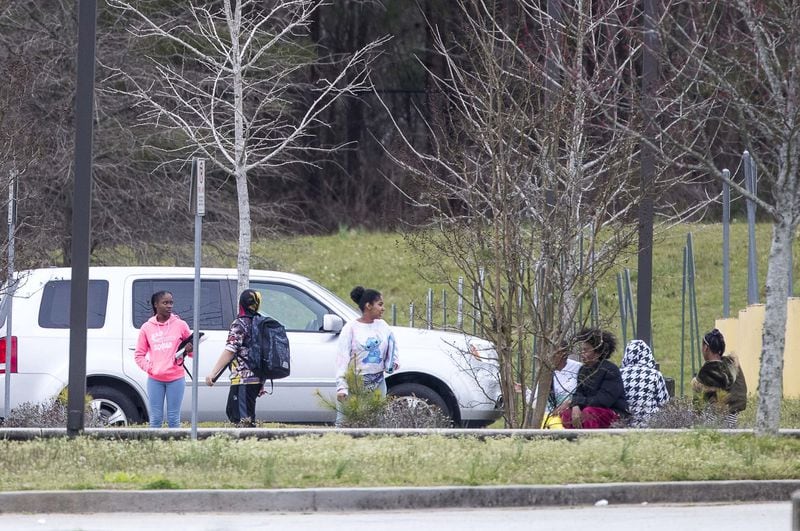 Students wait outside at Woodland Middle School in East Point, Monday, March 9, 2020. The Fulton County School system has decided to close schools on Tuesday after a teacher tested positive with the coronavirus. A decision on whether to keep the schools closed longer was expected Tuesday evening. 