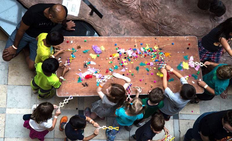 Youths gather around a table and grab items using robot arms they made from Popsicle sticks during Robots Day at the Fernbank Museum of Natural History on Saturday, June 23, 2018. (STEVE SCHAEFER / SPECIAL TO THE AJC)