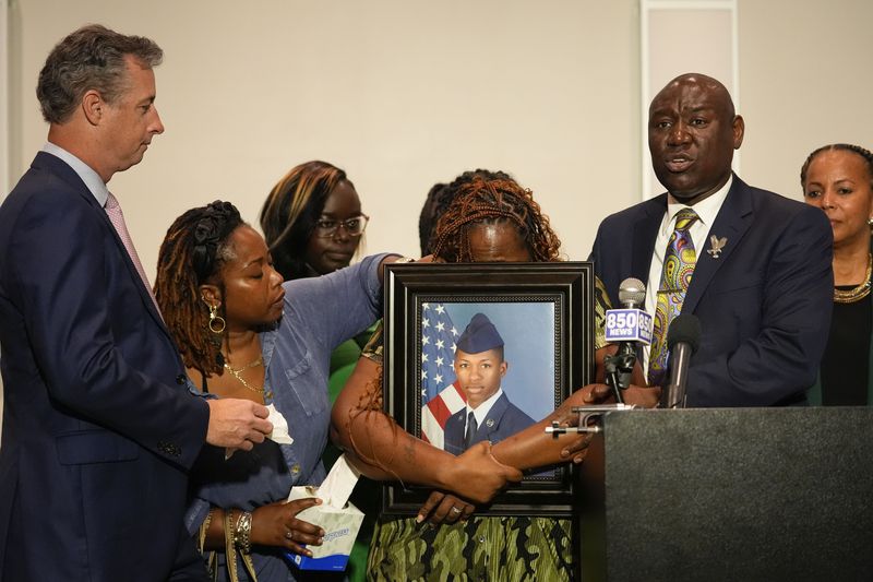 Chantimekki Fortson, mother of Roger Fortson, a U.S. Navy airman, weeps as she holds a photo of her son during a news conference regarding his death, along with family and Attorney Ben Crump, right, and Brian Bar, left, Thursday, May 9, 2024, in Ft. Walton Beach, Fla. Fortson was shot and killed by police in his apartment on May 3, 2024. (AP Photo/Gerald Herbert)