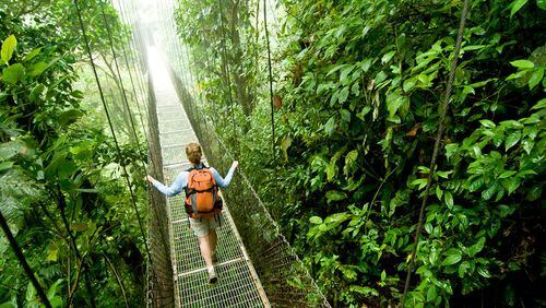 A young woman hikes along a hanging bridge near Arenal Volcano National Park in Costa Rica.