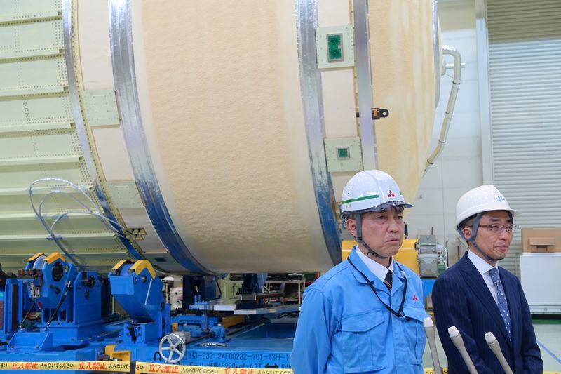 FILE - JAXA H3 rocket project managers Masashi Okada, right, and Mayuki Niitsu brief journalists in front of the second stage of a H3 rocket, set for a full-fledged launch later this year after two test flights, inside the Mitsubishi Heavy Industries' Nagoya Aerospace Systems Works Tobishima Plant in Tobishima, Aichi prefecture Thursday, March 21, 2024. Japan’s space agency announced Friday, April 26, that it will launch its new flagship rocket H3 on June 30 carrying an observation satellite for disaster response and security purposes, a key mission that it had failed in its debut flight last year. (AP Photo/Mari Yamaguchi, File)