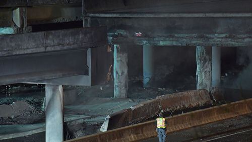 March 30, 2017 Atlanta - Crew surveys the section of an overpass that collapsed from a fire on I-85 on Thursday, March 30, 2017. Fire officials extinguished a massive fire on I-85 on Thursday night after it burned for more than an hour and led to the collapse of a bridge on the interstate, fire officials said. HYOSUB SHIN / HSHIN@AJC.COM