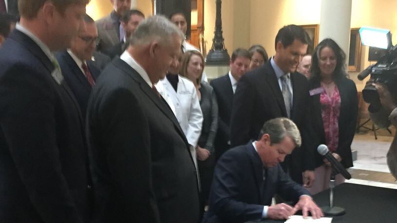 Gov. Brian Kemp, flanked by House Speaker David Ralston and Lt. Gov. Geoff Duncan, with Sen. Blake Tillery on the far left, signs Senate Bill 106, the Medicaid and ACA waiver bill, on March 27. (PHOTO by Ariel Hart / ahart@ajc.com)