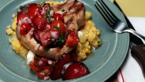 Whiskey-brined pork chops topped with tomato-plum relish served atop sweet corn and chive polenta. (Terrence Antonio James/Chicago Tribune/TNS)