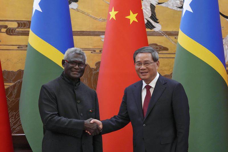 FILE - Visiting Solomon Islands Prime Minister Manasseh Sogavare, left, shakes hands with his Chinese counterpart Li Qiang after they witnessed signing on agreement for both countries at the Great Hall of the People in Beijing, July 10, 2023. Current Prime Minister Sogavare, who switched the Solomons' allegiances from Taiwan to Beijing and ignited fears of China gaining a naval foothold in the South Pacific in his current five years in power, is seeking an unprecedented second consecutive term at the government's helm when the Solomon Islands goes to the polls on Wednesday, April 17, 2024. (AP Photo/Andy Wong, Pool, File)