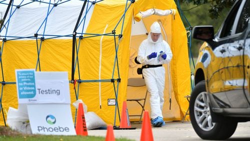 A medical professional in protective gear prepares to collect a sample from a potential COVID-19 patient at a Phoebe Putney Health System drive-through testing site in Albany. (Hyosub Shin / Hyosub.Shin@ajc.com)