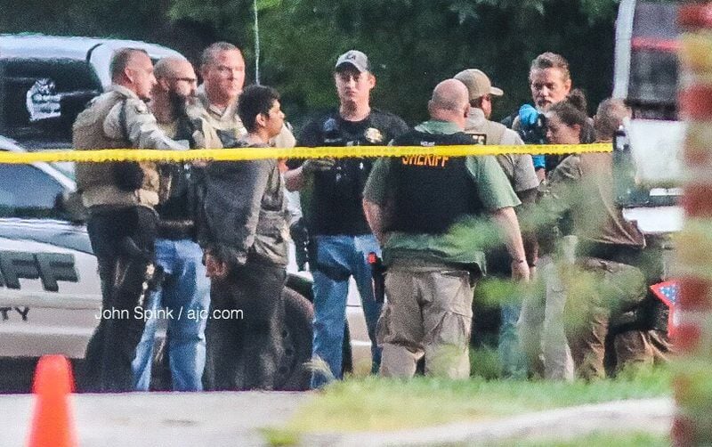 Authorities place a man in handcuffs Monday morning at the scene of a deadly officer-involved shooting in Gainesville. 