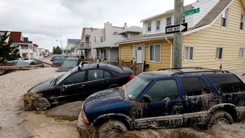 In this Oct. 30, 2012 file photo, cars lifted by floodwater are mired in several feet of sand in the aftermath of Superstorm Sandy, in Long Beach, N.Y.
