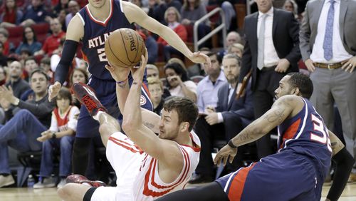 Houston Rockets' Donatas Motiejunas, center, passes off the ball from the floor between Atlanta Hawks Kyle Korver, left, and Mike Scott (32) in the first half of an NBA basketball game Saturday, Dec. 20, 2014, in Houston. (AP Photo/Pat Sullivan)