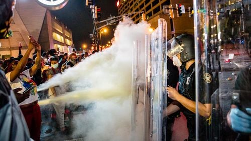 Protesters spray fire extinguishers at police as they clash Friday evening  at the corner of Marietta Street and Centennial Olympic Park in the summer of 2020. Legislation that cleared a state Senate panel this week would impose harsher penalties on people who commit crimes during protests.