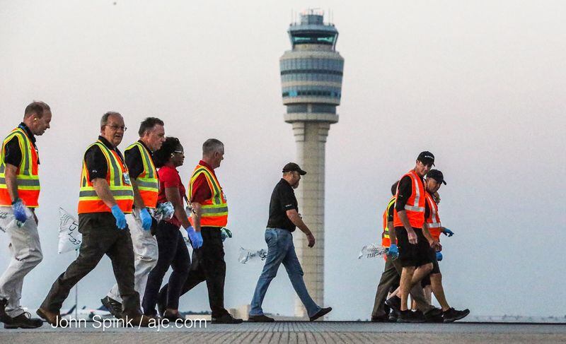 Nearly 100 airport employees were picking up debris along a runway before the sun came up Wednesday.  JOHN SPINK / JSPINK@AJC.COM