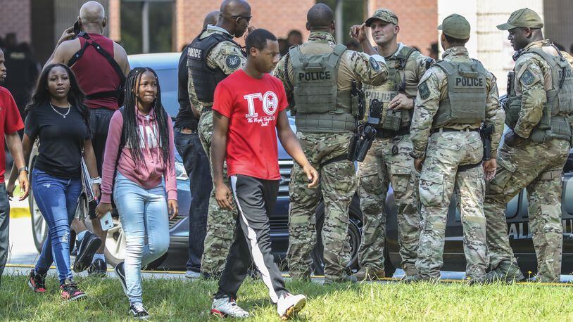 Stephenson High School students walk past DeKalb County SWAT officers outside the school Tuesday morning, Aug. 13, 2019. Officers burst into classrooms with guns drawn after a student reported seeing an armed classmate. The gun scare prompted a heavy police presence, road closures and a Level 3 lockdown at the school on Stephenson Road in Stone Mountain. JOHN SPINK/JSPINK@AJC.COM