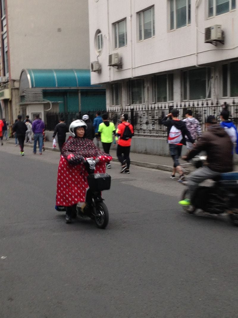 Mopeds are very popular in Shanghai and Hangzhou because of the traffic. What's a little different about them in China is that the riders are of all ages; that they're electric, so they sneak up on you if you're walking in the street; and a lot of the riders use gear like this woman to block the wind.