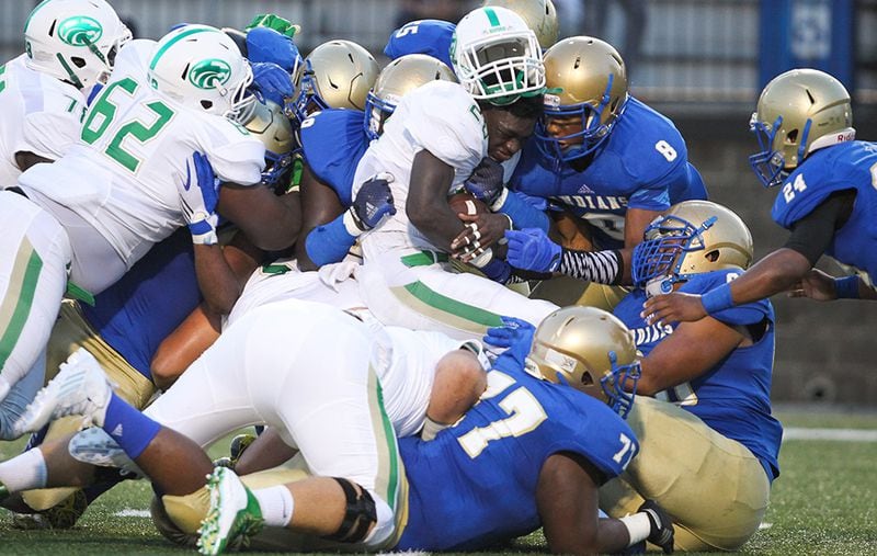 Buford's Anthony Grant (center) is tackled by McEachern defenders during the first half at Walter H. Cantrell Stadium in Powder Springs, Friday, Sept. 4, 2015.