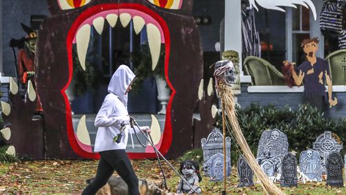 Kristy Turner walks her two dogs, Maeby and Buster, in the rain past a spooky home in the 300 block of Atlanta Avenue in the Grant Park neighborhood Friday morning. The rain should clear out by Sunday in time for a try, but still spooky, Halloween, according to Channel 2 Action News.