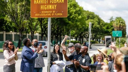 Isabella Banos, center, of the Harriet Tubman Highway Committee, joined by her grandfather, Modesto Abety, and local elected officials, smiles after unveiling the new sign renaming a portion of South Florida’s Dixie Highway after Harriet Tubman on Sept. 18.
