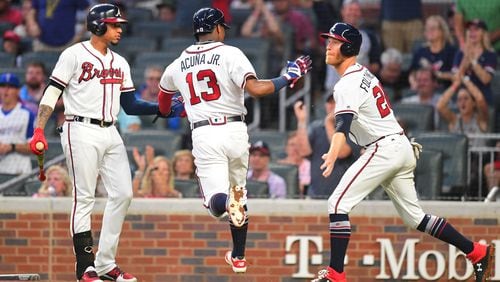 Mike Foltynewicz and Johan Camargo congratulate Ronald Acuna after Acuna scored   a third-inning run against the Colorado Rockies at SunTrust Park on Saturday.