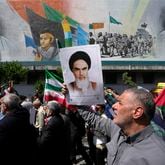 FILE - Iranian worshippers walk past a mural showing the late revolutionary founder Ayatollah Khomeini, right, Supreme Leader Ayatollah Ali Khamenei, left, and Basij paramilitary force, as they hold posters of Ayatollah Khomeini and Iranian and Palestinian flags in an anti-Israeli gathering after Friday prayers in Tehran, Iran, April 19, 2024. This month's unprecedented direct attacks between Iran and Israel are revealing deeper insights into both militaries. Experts say Friday's apparent precision strike by Israel deep into Iran demonstrated Israel's military dominance on almost all fronts. (AP Photo/Vahid Salemi, File)