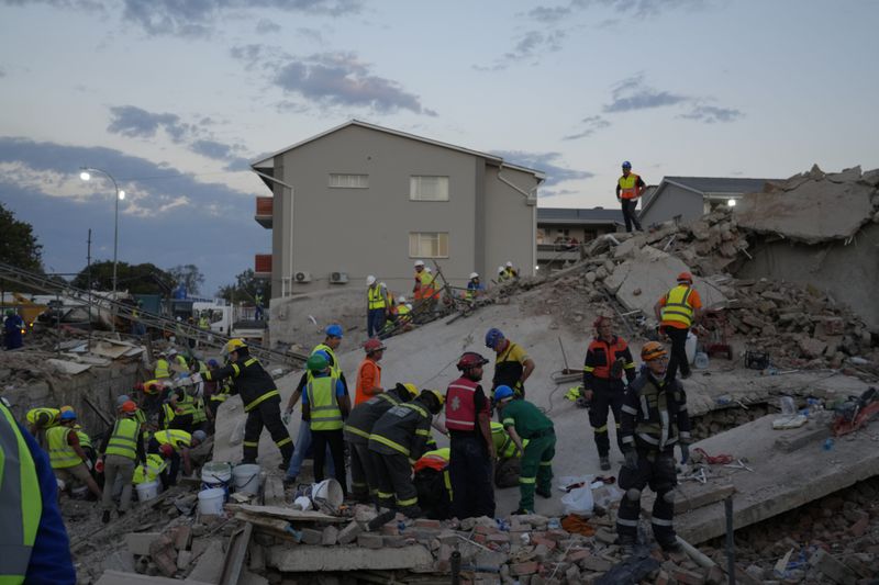 Emergency workers on the scene of a building collapse in the city of George, about 400 kilometers (250 miles) east of Cape Town, South Africa, Tuesday, May 7, 2024. Rescue teams trying to find dozens of construction workers missing since a multi-story apartment complex collapsed in a coastal city in South Africa have made contact with 11 people buried alive beneath the mangled wreckage, authorities said Tuesday. (AP Photo/Nardus Engelbrecht)