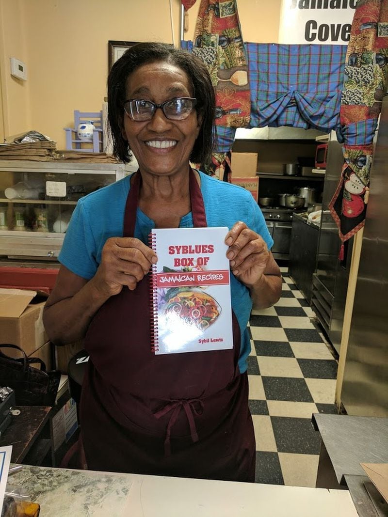 Jamaica Cove chef-owner Sybil Lewis with her new cookbook, “Syblues Box of Jamaican Recipes.” CONTRIBUTED BY PAULA PONTES