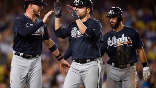 CORRECTS PLAYER AT LEFT TO TYLER FLOWERS, INSTEAD OF ENDER INCIARTE - Atlanta Braves' Jaime Garcia, center, celebrates with Tyler Flowers, left, after hitting a grand slam off Los Angeles Dodgers starting pitcher Alex Wood, as Sean Rodriguez trails during the fifth inning of a baseball game in Los Angeles, Friday, July 21, 2017. (AP Photo/Kelvin Kuo)