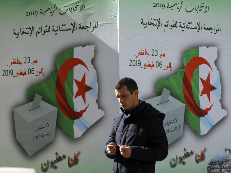FILE - A man walks past a poster asking citizen to register to vote in Algiers, Feb. 5, 2019. President Abdelmadjid Tebboune's surprise decision to schedule elections earlier than expected in Algeria is prompting suspicion and appears to be awakening discouraged political parties from a deep lethargy. (AP Photo/Anis Belghoul, File)