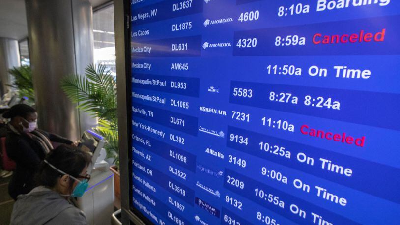 Travelers check for flight information at Los Angeles International Airport in Los Angeles on Dec. 24, 2021. (David McNew/AFP via Getty Images/TNS)