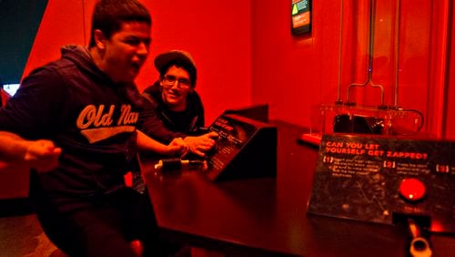 In this file photo, Jose Alfredo Santiago (left) jumps out of his seat after being given a small electric shock as Fernando Vergara watches in an interactive display in the Goosebumps: The Science of Fear exhibit at the Fernbank Museum of Natural History in 2014. A new evening series will give adults a chance to try all sorts of hands-on science experiments.  JONATHAN PHILLIPS / SPECIAL